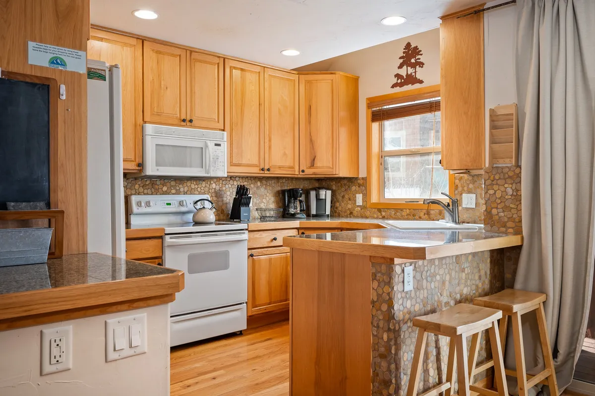 A modern chef’s kitchen with a spacious island and comfortable stools, surrounded by sleek cabinetry, high-end appliances, and abundant natural light streaming through the windows. The kitchen feels open and inviting, ideal for cooking, enjoying a gourmet coffee, or hosting friends and family.